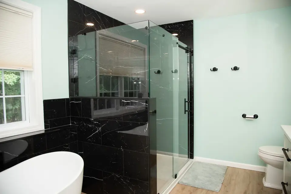 Walk-in glass shower with black marble tile