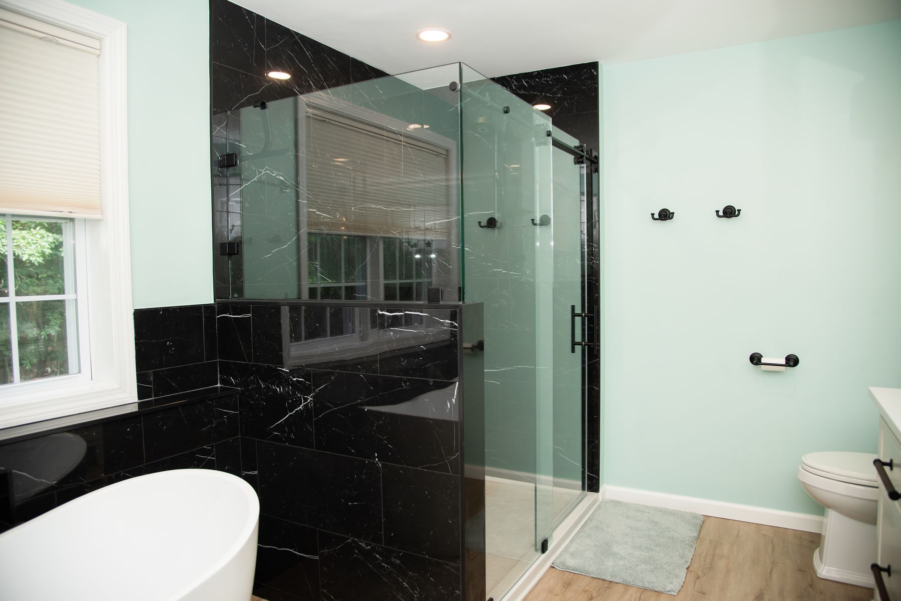 Walk-in glass shower with black marble tile