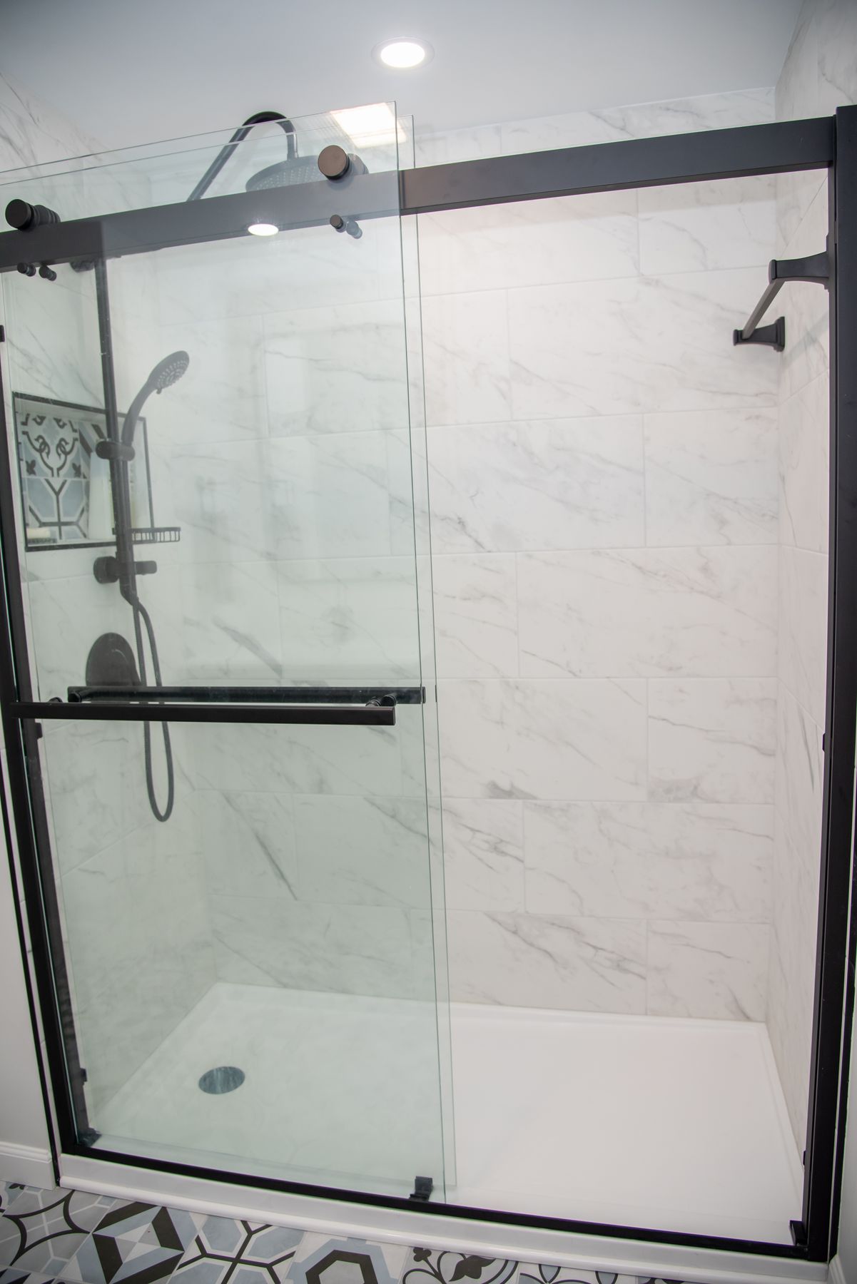 Marble tile walk-in shower with sliding glass doors