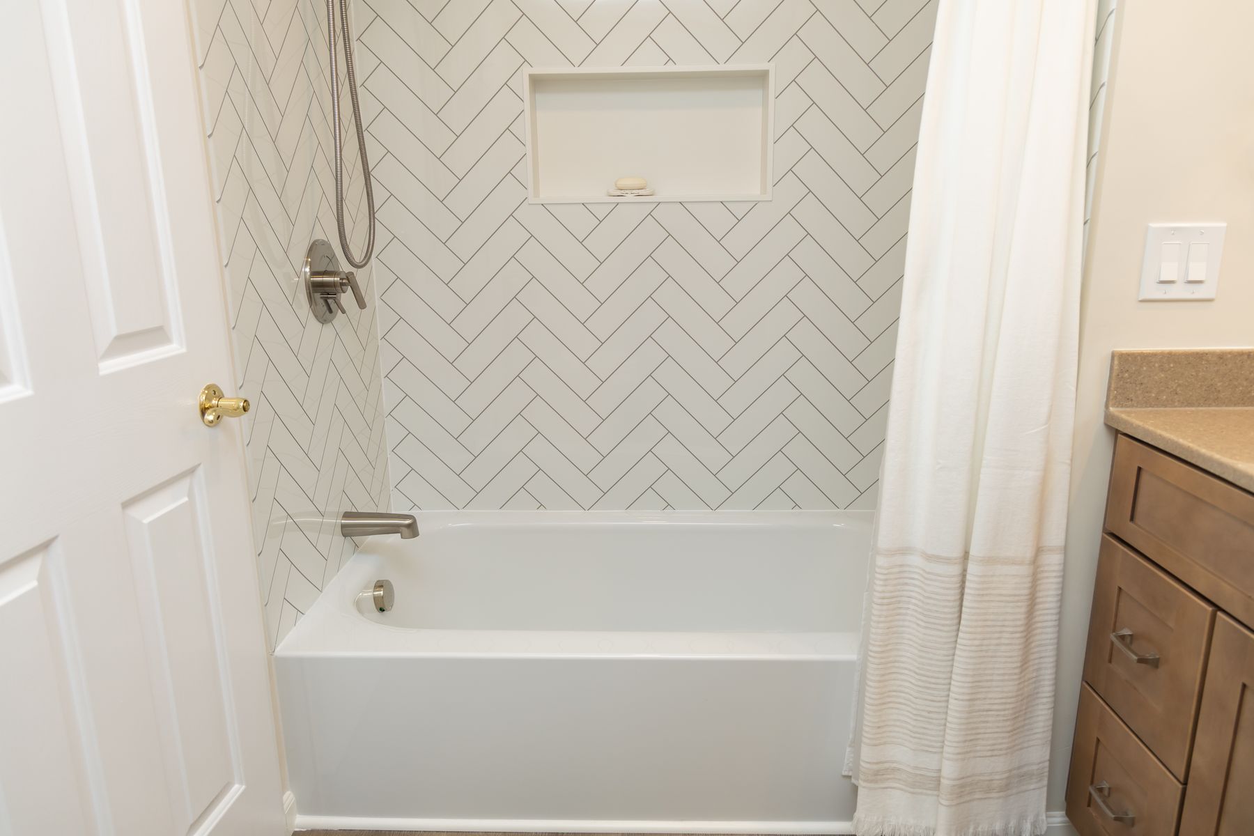 Herringbone tile tub surround with a built-in niche