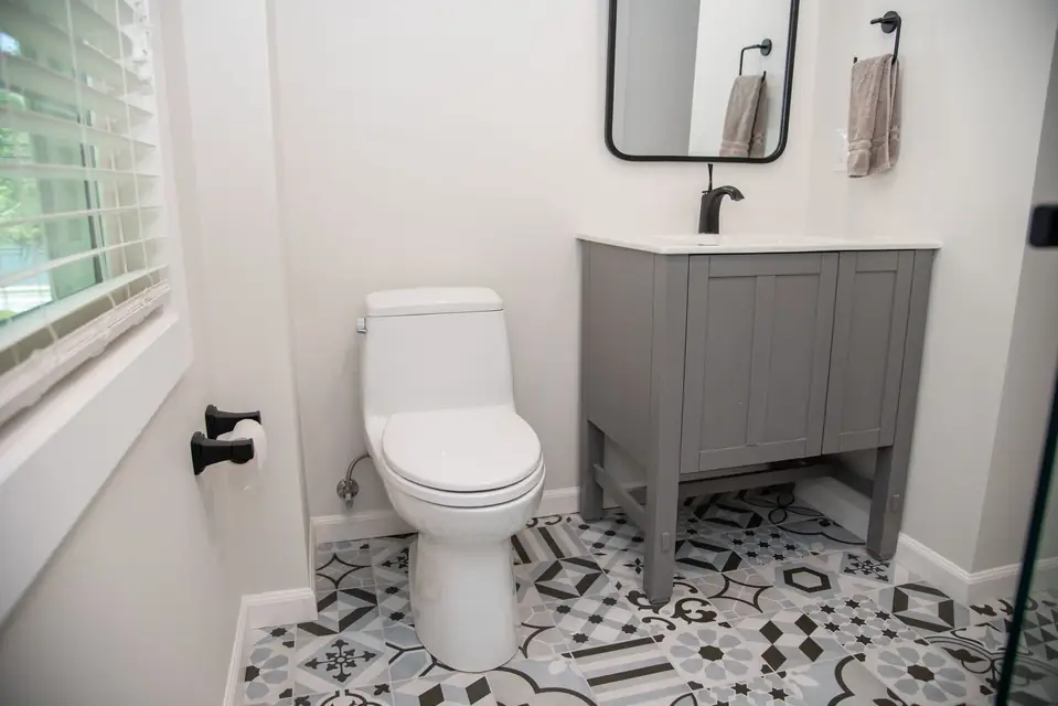 Powder room with patterned floor tile and a gray vanity