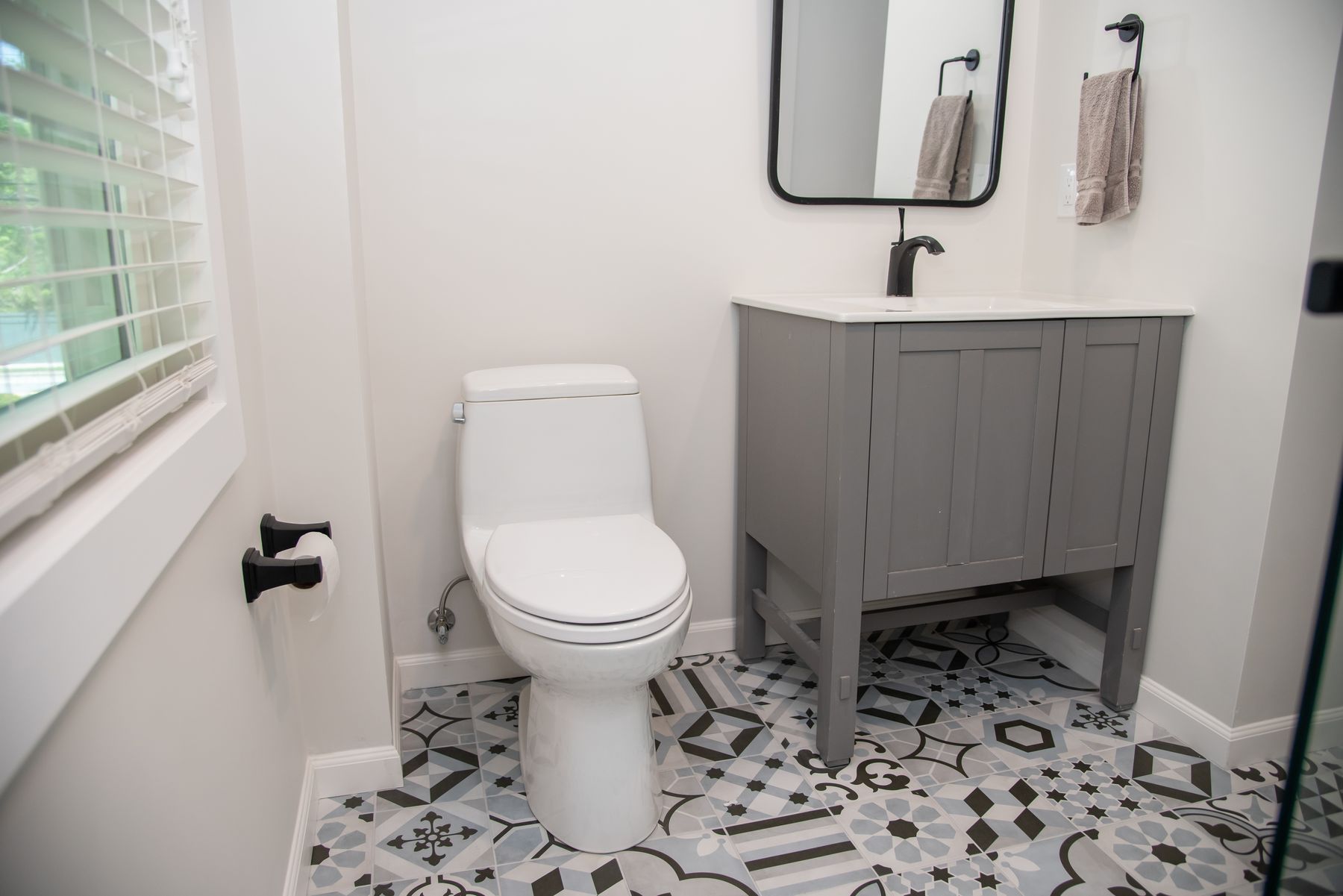 Powder room with patterned floor tile and a gray vanity
