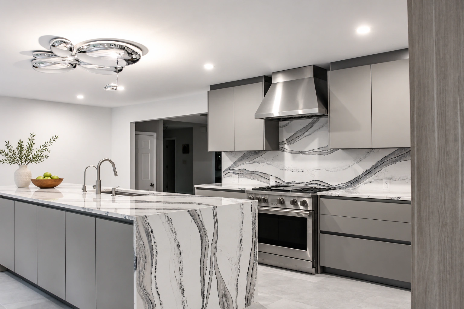 A gray kitchen with a waterfall marble island and stainless range