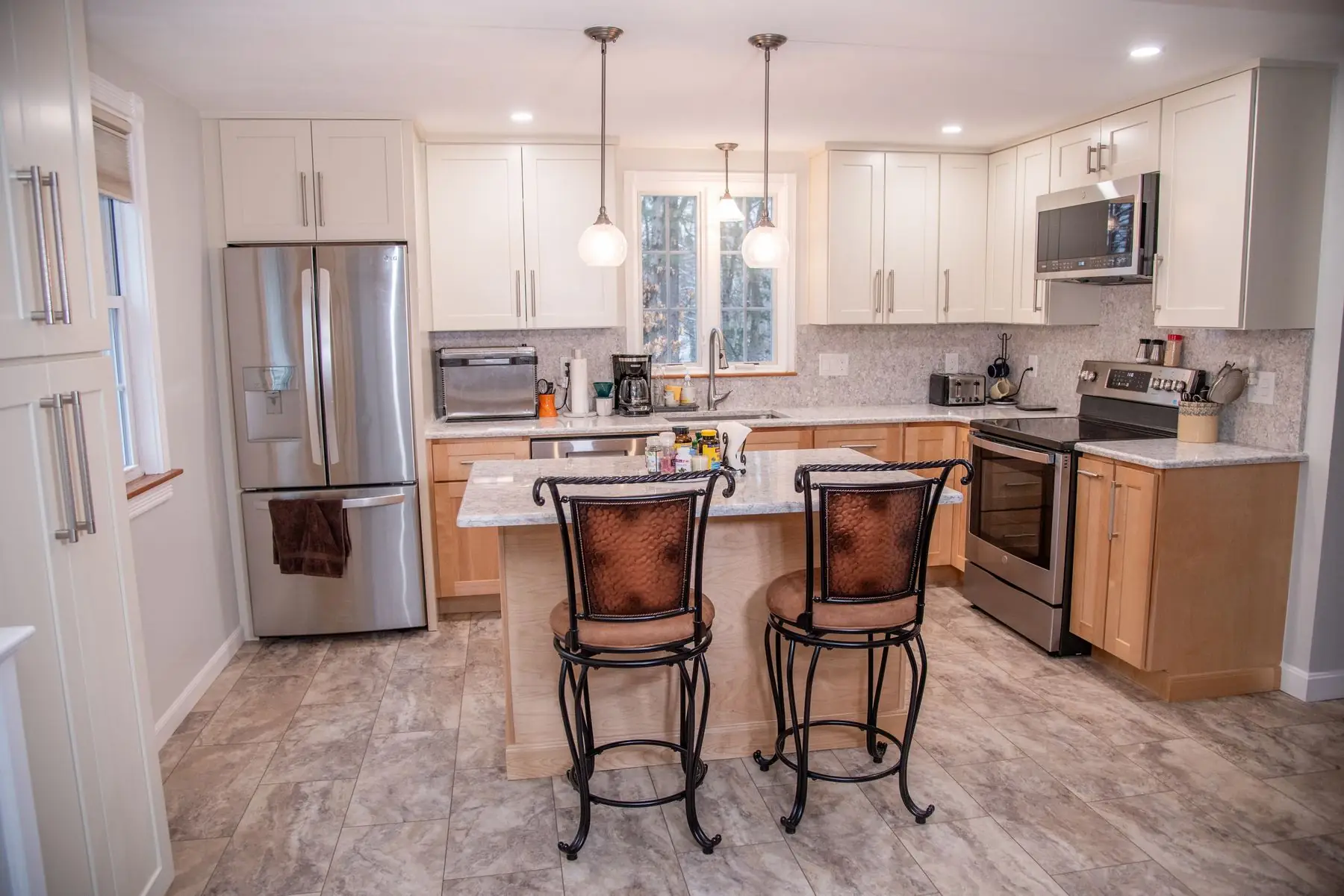 A remodeled kitchen with white shaker cabinets and a maple island